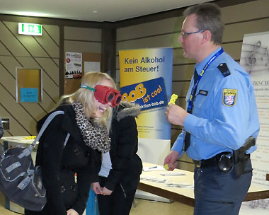 Eine junge Dame versucht mit der Rauschbrille den BOB-Schlüsselanhänger von Dirk Wussow zu greifen - ohne Erfolg