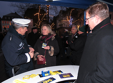 PHK Dirk Brandau (links) informiert zusammen mit Polizeipräsident Bernd Paul (rechts) eine Besucherin des Weihnachtsmarktes in Gießen über die Aktionen der Polizei