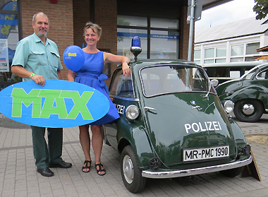 Auch Hans-Peter Kaletsch vom Polizeioldtimer-Team in historischer Polizeiuniform zusammen mit eine Festivalbesucherin im Petticoat mit dem MAX-Schriftzug und der BMW-Isetta