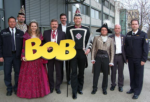 v.l. POK Jörg Pfeiffer mit dem Gießener Prinzenpaar samt Gefolge, sowie Polizeipräsidet Manfred Schweizer (4. v.l.), Projektleiter Manfred Kaletsch (rechts) und einem überdimensionalen BOB-Anhänger
