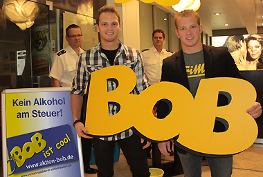 Nach dem erfolgreichen Rauschbrillentest ein Bild mit dem großen BOB-Schriftzug, Fabian Hambüchen, Fabian Lotz und das BOB-Team