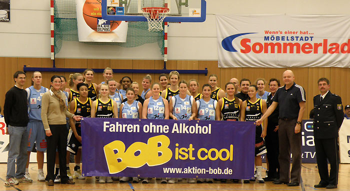 Gruppenbild der Damen-Basketball-Bundesliga-Teams von BC Pharmaserv Marburg und TV Saarlouis Royals mit dem BOB-Banner sowie den Trainern und Betreuern und POK Martin Frank vom BOB-Team der Polizei (ganz rechts)