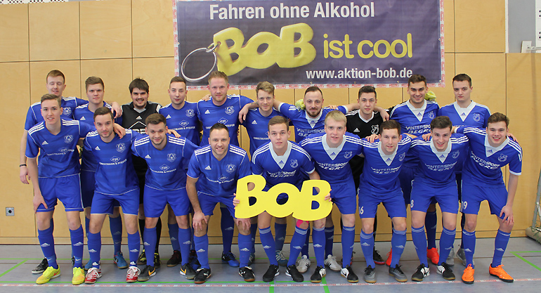 Die Mannschaften vom FV Wiesenbach und FV Breidenbach mit dem BOB-Werbebanner und -BOB-Schriftzug 