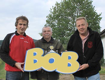 v.l. Die Vorsitzenden des FSV Buchenau, Frank Löber (links) und Lothar Dönges (rechts) halten zusammen mit Kreisfußballwart Heinz Schmidt den BOB-Schriftzug