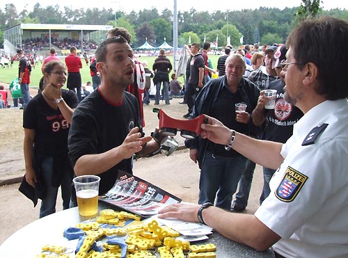 Polizeioberkommissar Konrad Damm bietet einem Fan einen Rauschbrillentest an