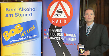 Polizeidirektor Manfred Kaletsch mit der Senator-Lothar-Danner-Medaille in Gold - neben den Plakaten der Aktion BOB und des B.A.D.S.